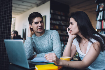 Busy coworkers discussing project in cafeteria sitting at table with planner and netbook