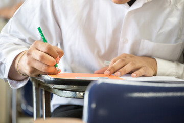 high school,university student study.hands holding pencil writing paper answer sheet.sitting lecture chair taking final exam attending in examination classroom.concept scholarship for education abroad