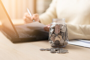Woman looking for the bills ready to pay. Coins in a jar concept of saving for household expenses....