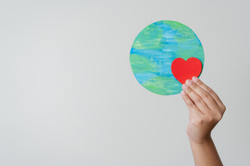 Woman hand holding heart shape with the world elements to empowered environmental conservation.