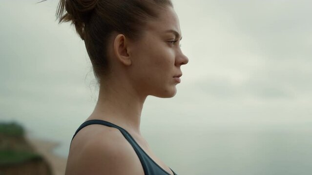 Sportswoman looking ahead standing beach closeup. Girl making breathing exercise