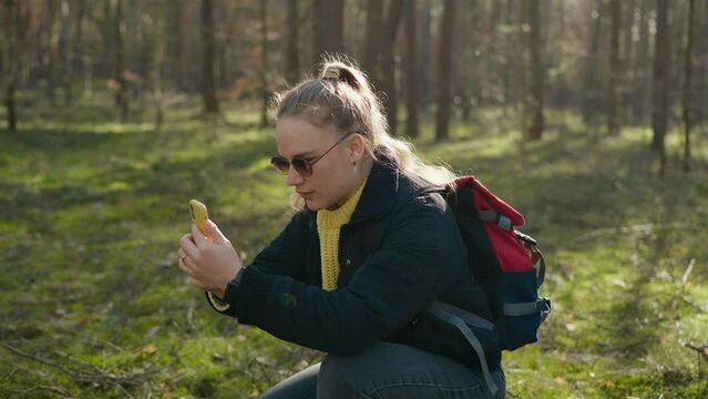 girl takes a picture on the phone in the forest