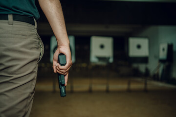 Professionals carry a 9mm pistol inside a shooting range.