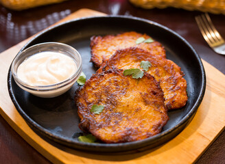 Fried grated potato pancakes with sour cream on frying pan