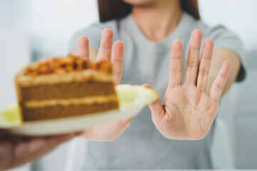 Asian women is fighting a diet by reject  to eat cake to keep it from getting fat