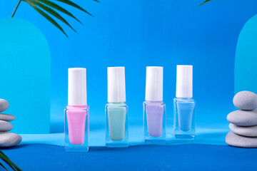 Collection of nail polish of pastel colors in unlabeled vials in line on blue background with palm...