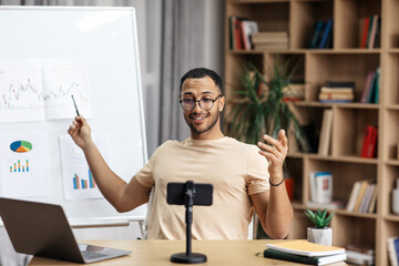 Young arab man making business presentation and demonstrating graphs on whiteboard