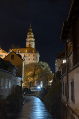 Fototapeta na wymiar Castle of Cesky Krumlov at night. The slow flowing river Vltava is in the foreground. Vertically.