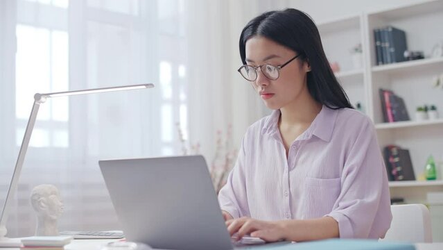 Asian woman writer typing on laptop, massaging stiff neck, sedentary lifestyle