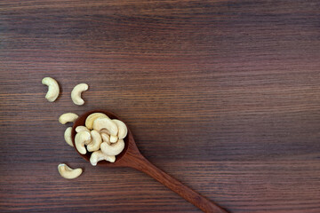 Roasted cashew nut in spoon on wooden texture background