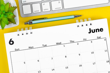 June 2022 desk calendar with pen and keyboard computer on yellow background. - obrazy, fototapety, plakaty