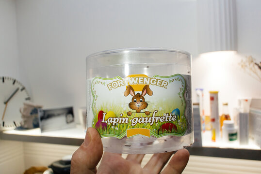 Paris, France - Apr 29, 2022: Male hand holding empty plastic recipient with Fortwenger Lapin gaufrette - delicious Alsatian rabbit for the easter holiday