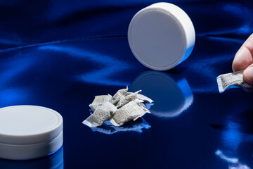 Closeup of white Swedish snus pouches against a blue background. Smokeless tobacco.