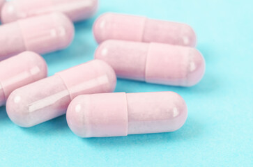 Pink capsule pills on blue background.
