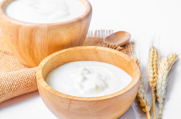 Greek yogurt in a wooden bowl and dry barley on table.