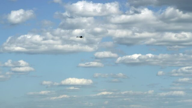 A small plane is flying against the background of a blue sky with large white clouds. A gray propeller plane flies on a sunny day of a heavenly landscape. Film grain texture. Pixel texture.