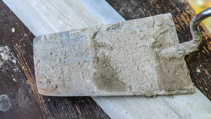 Close-up of a dirty trowel on wooden background. Wall renovation process. Renovation concepts.