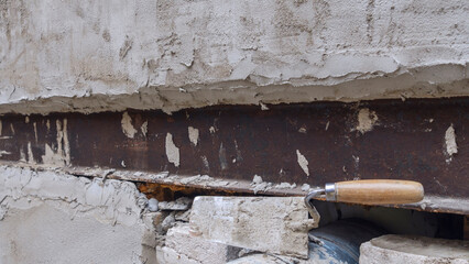 Close-up of a dirty trowel against a wall with plaster. Wall renovation process. Renovation concepts.