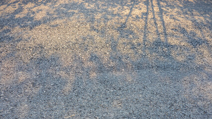 Background of paved road surface with sunlight shining through the shadow.