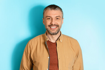 Portrait Of Happy Middle Aged Man Over Blue Background