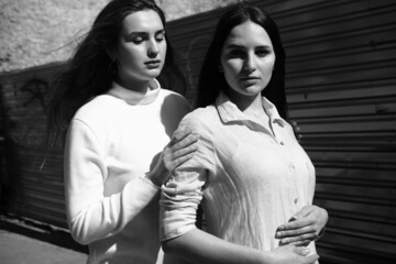 Black and white portrait of two girls. Girls in white dresses walking in the park