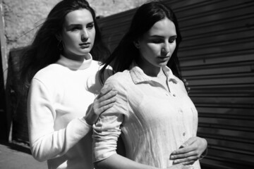 Black and white portrait of two girls. Girls in white dresses walking in the park