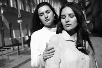 Black and white portrait of two girls. Girls in white dresses walking in the park