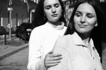 Fototapeta premium Black and white portrait of two girls. Girls in white dresses walking in the park