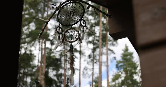 Dream catcher dancing in the wind in a forest. Indian amulet dreamcatcher swaying in the wind on a spring forest background. 4k footage with copy space.