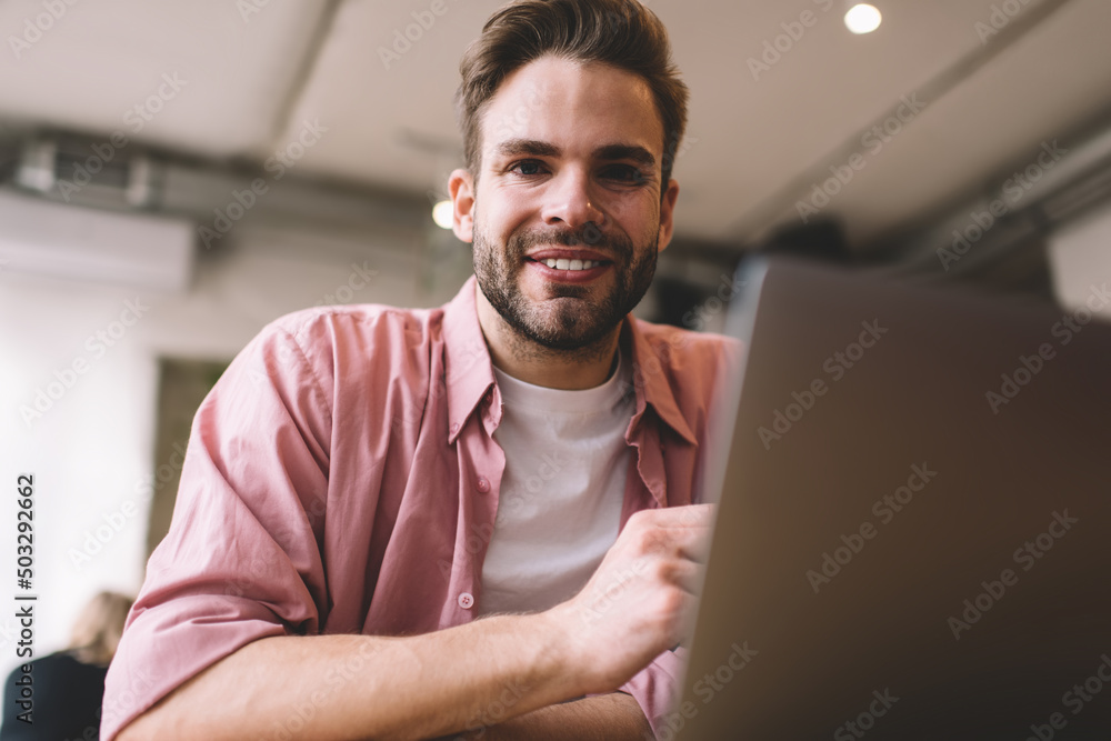 Poster portrait of cheerful male freelancer with digital laptop technology for web programming smiling at c