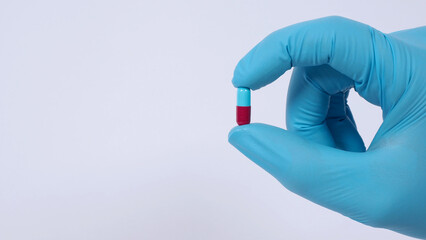 Taking or holding medication pills in hand. Capsule pill on white background isolated. Nitrile disposable gloves and medicines. Drugs healthcare treatment and supplement relieve symptoms of COVID 19.