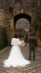 A weeding day and the bride walking towards the groom in a medieval town in italy.