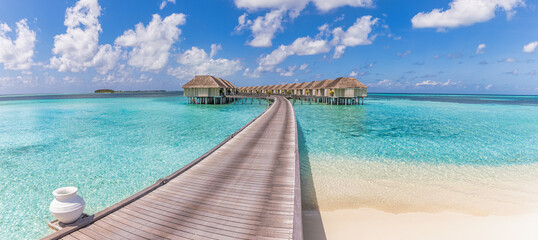 Beautiful Maldives water villa in blue lagoon and blue sky space. Panoramic summer landscape, ocean lagoon with relaxing idyllic cloudy blue sky. Exotic luxury travel background. Amazing Maldives view