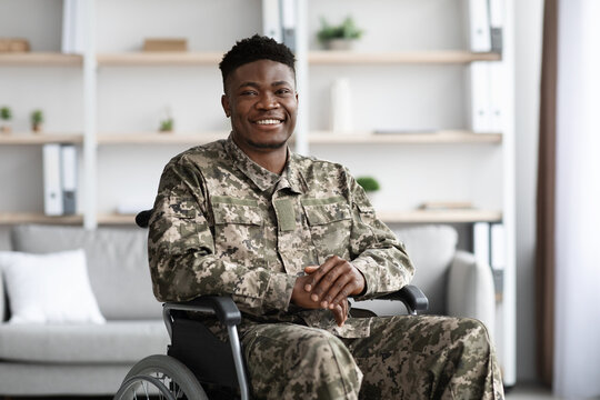 Positive african american military man sitting in wheelchair, clinic interior