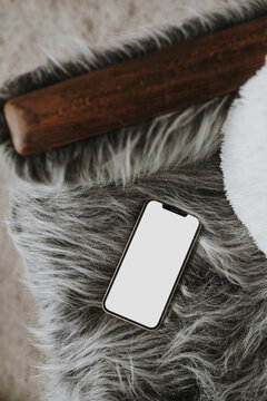 Flatlay mobile phone on fluffy woolen chair. Aesthetic elegant blog, social media, online store template with copy space