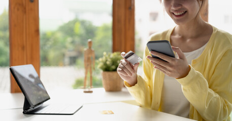 Close up of girl hold bank credit card, shopping online using mobile phone, buying goods or ordering online, entering bank accounts and details in online banking offer.