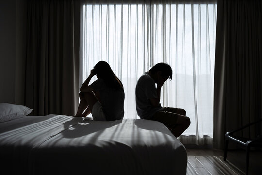 Depressed couple having a problem sitting head in hands in the dark bedroom, Negative emotion and mental health concept