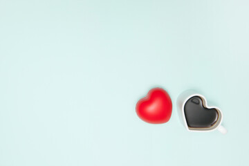 Heart shape coffee cup with soft red heart over light blue background. View from above. Flat lay.