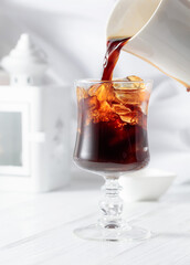 Black coffee is poured into a glass with iced.