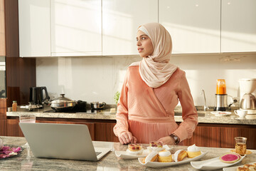 Muslim woman standing by kitchen table at home