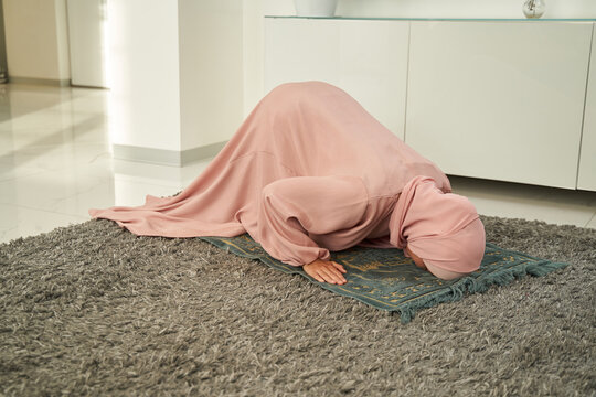 Muslim woman bowing down and prostrating on praying carpet