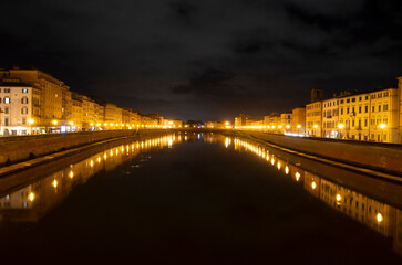 Arno river among the Pisa lights and a cloudy night sky after a rainy day.