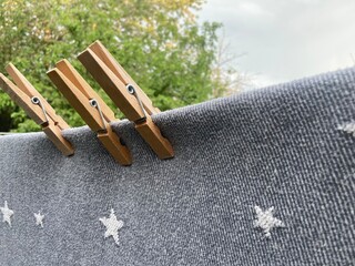 Three clothespins hold a gray cloth with stars