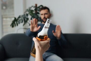 Man refusing to drink beer indoors, closeup. Alcohol addiction treatment
