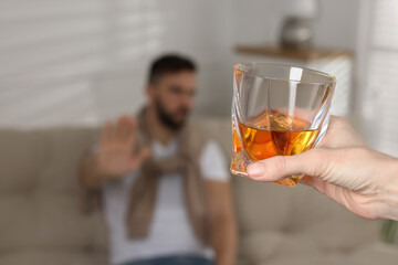 Man refusing to drink whiskey indoors, closeup. Alcohol addiction treatment