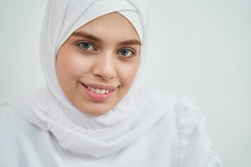 Cheerful Muslim young woman wearing white traditional hijab