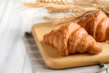 Homemade croissant on wood plate and on white wood background,