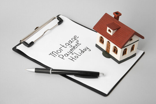 House Model, Clipboard With Text Mortgage Payment Holiday And Pen On Light Grey Table