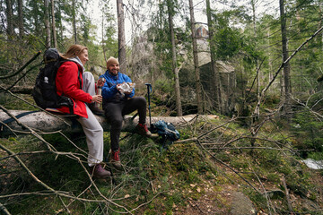 Obraz premium Pair of hikers taking a bite on fallen tree