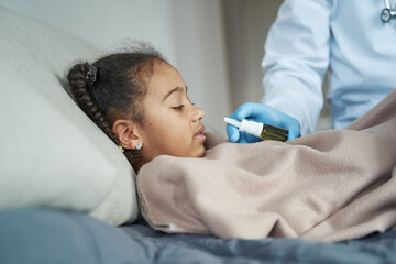 Obraz premium African American girl takes medicine in her nose